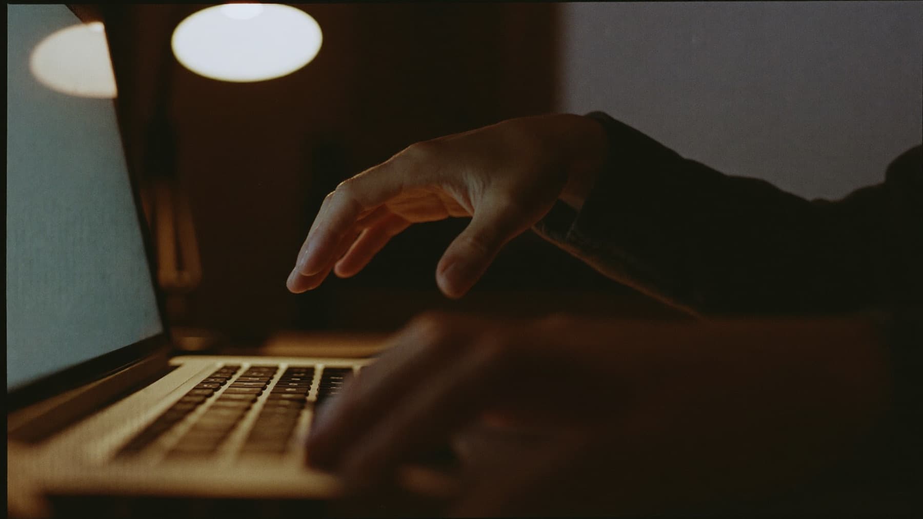 Hände, die über einer Laptop-Tastatur schweben, ohne sie zu berühren.